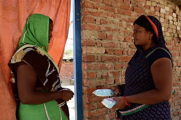 A community health leader sells sanitary napkins to a woman in Bihar, India. © Matthew Smeal