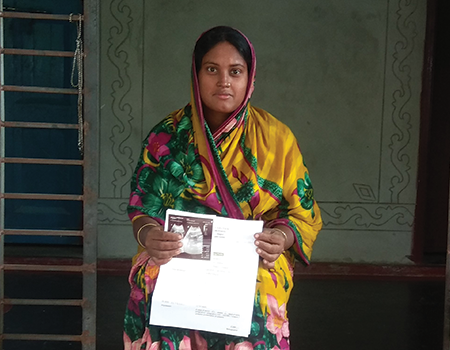 Kulsum holds up her scans in Bangladesh